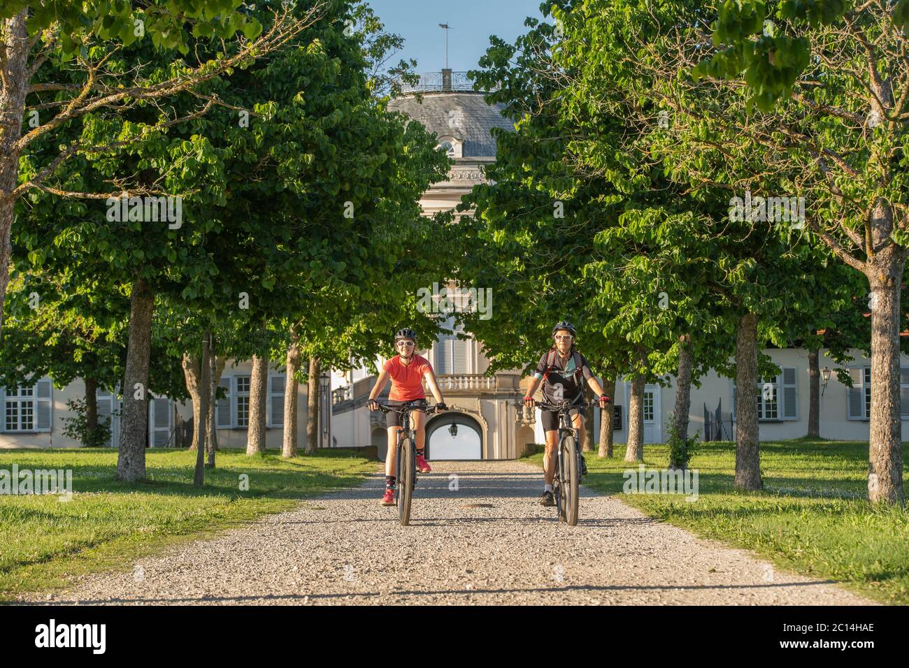 Nonna e nipote in sella alle loro mountain bike e divertirsi in un pomeriggio di sole di fronte al castello di Soliude vicino alla città di Stoccarda Foto Stock