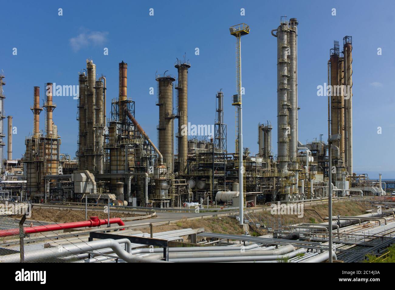 Tubi e macchinari industriali pesanti in un'area industriale a cielo blu a Sardina, Italia Foto Stock