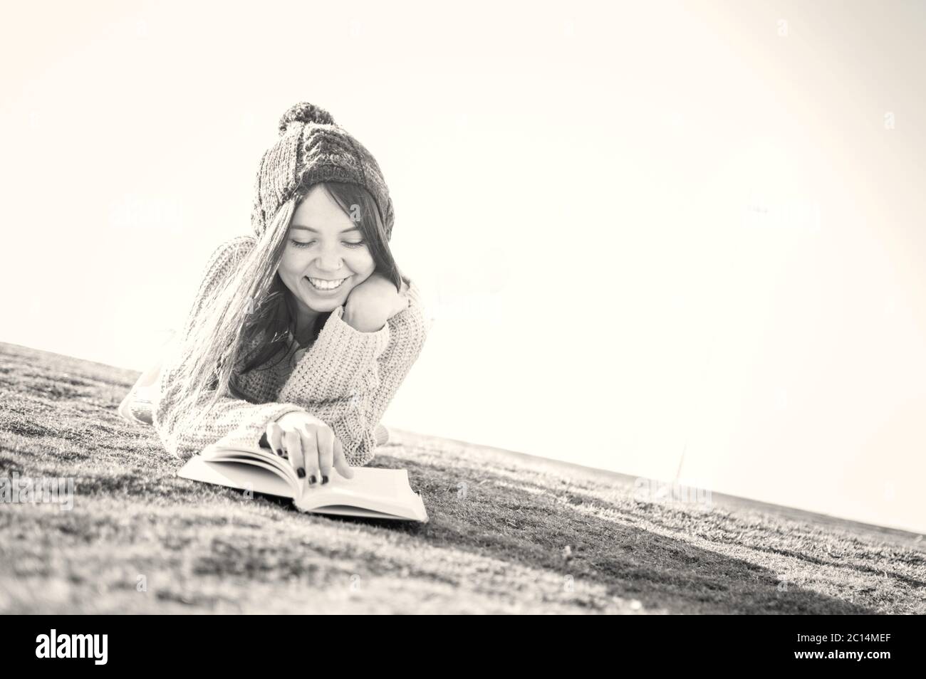 Giovane donna di 25 anni si gode mentre legge un libro da sola nel parco Foto Stock