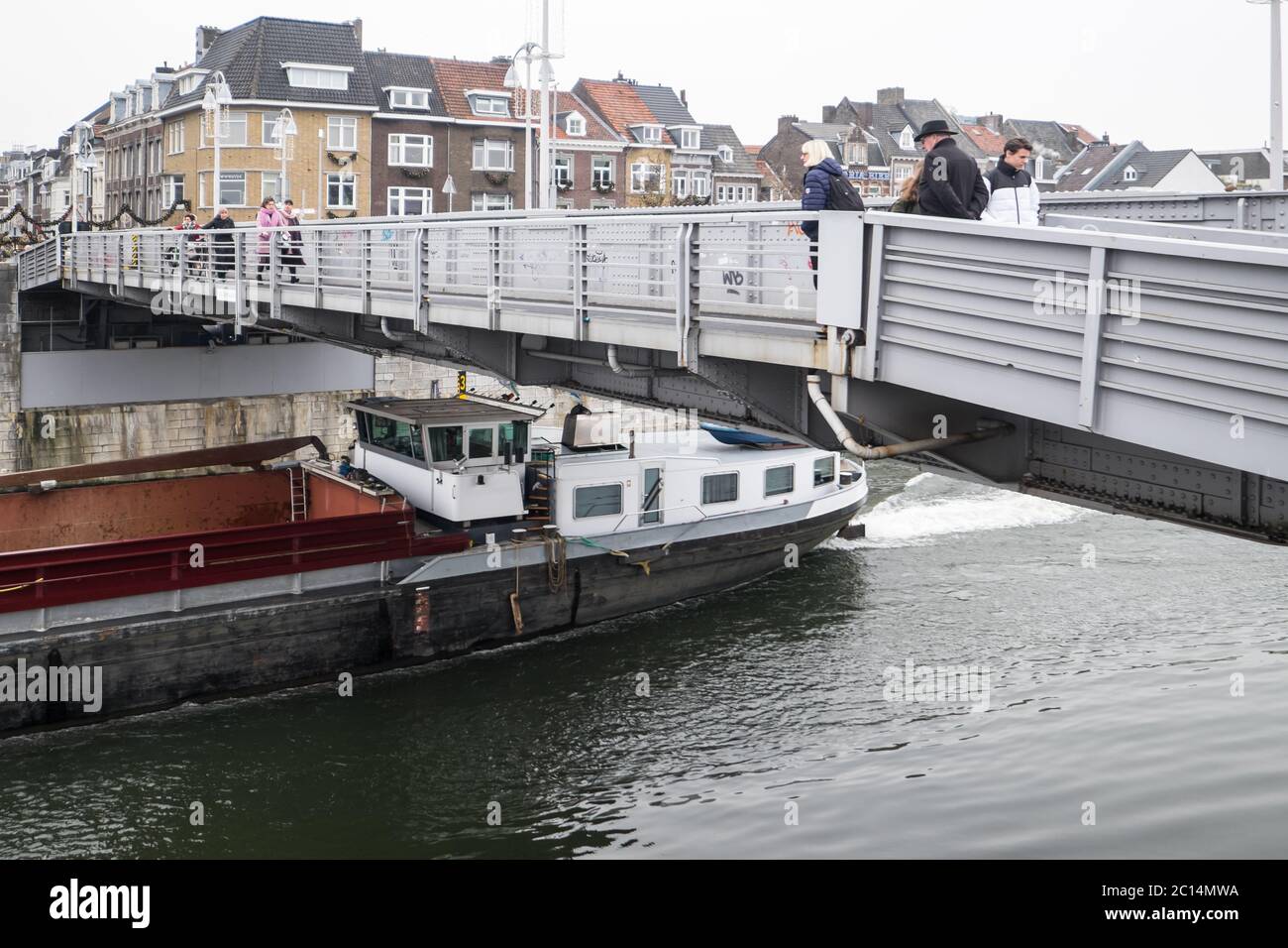 La nave da carico naviga nel fiume Mosa sotto il ponte Sint Servaas, la parte mobile è stata sollevata. I pedoni la attraversano Foto Stock