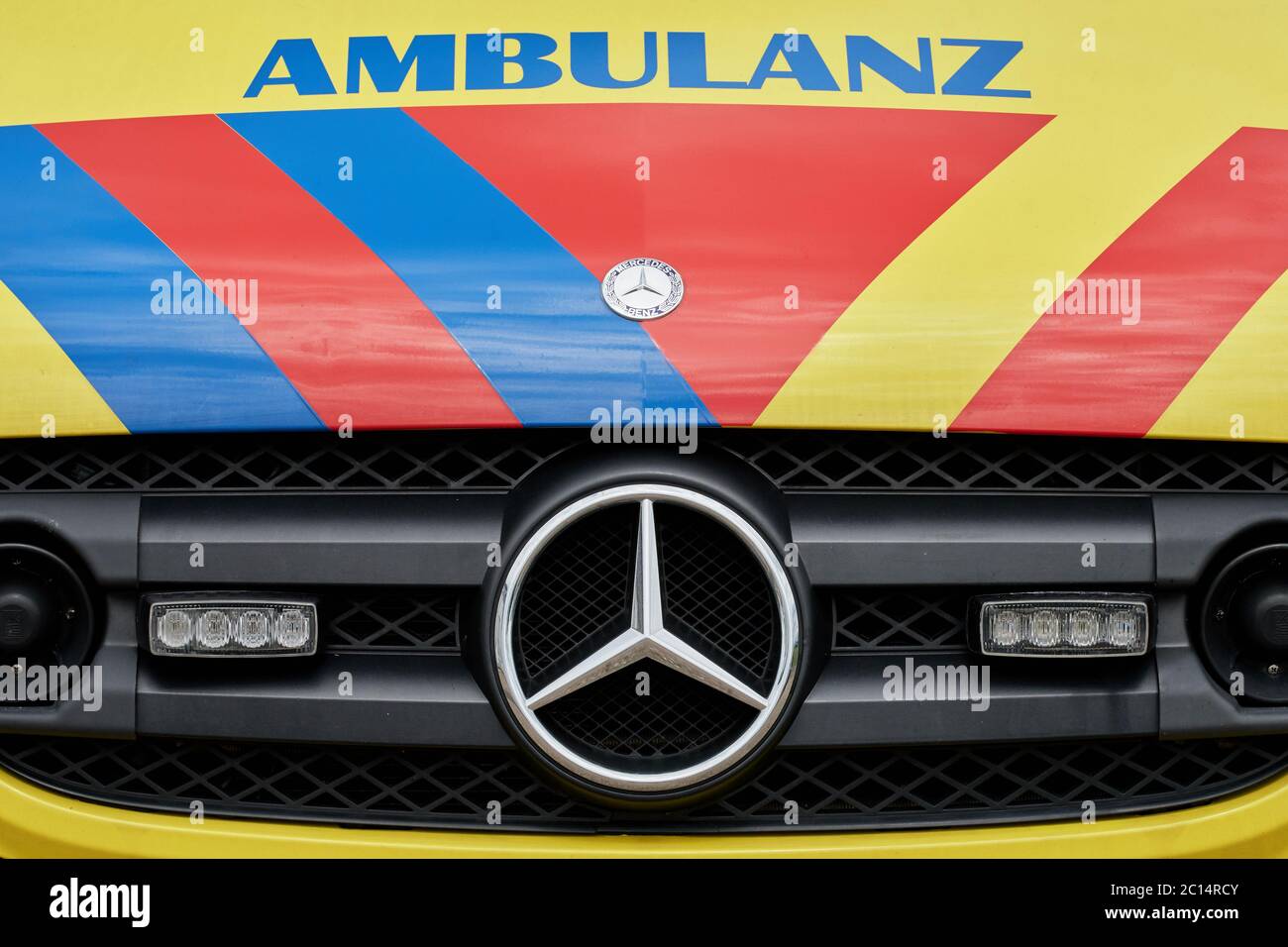 Primo piano della parte anteriore del furgone giallo dell'ambulanza a strisce rosse e blu, veicolo di emergenza con luci a LED Foto Stock