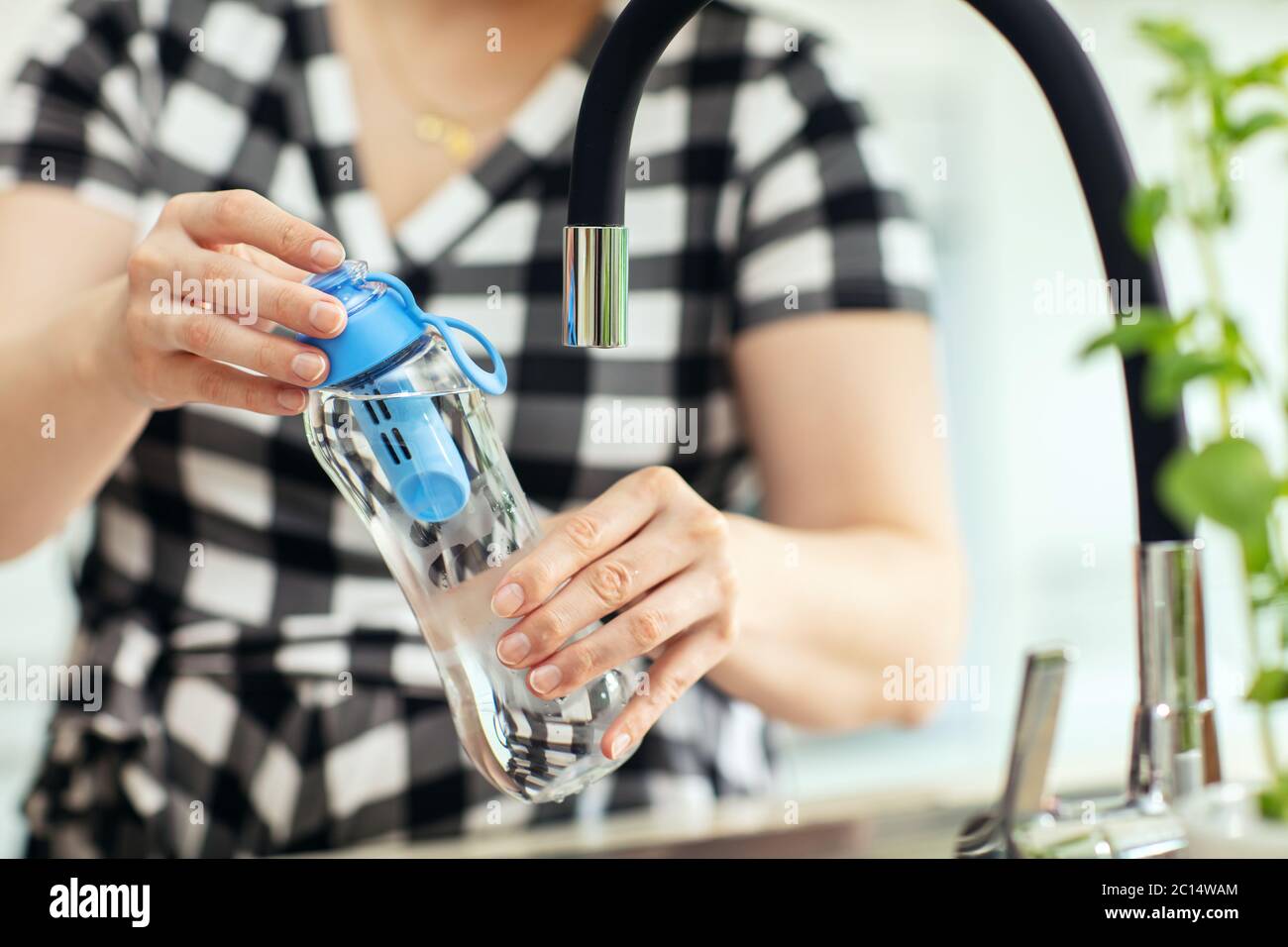 Donna avvitare il flacone. Donna si avvita sulla bottiglia riutilizzabile di acqua con filtro al carbonio in cucina Foto Stock