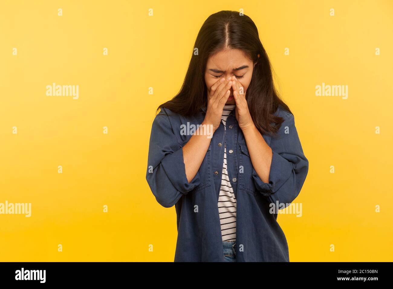 Ritratto di drammatica ragazza sconvolgente in camicia denim che piange con dolore, strofinando le lacrime, sentendosi solitario senza speranza, emozioni disperate, preoccupati per i problemi. Foto Stock