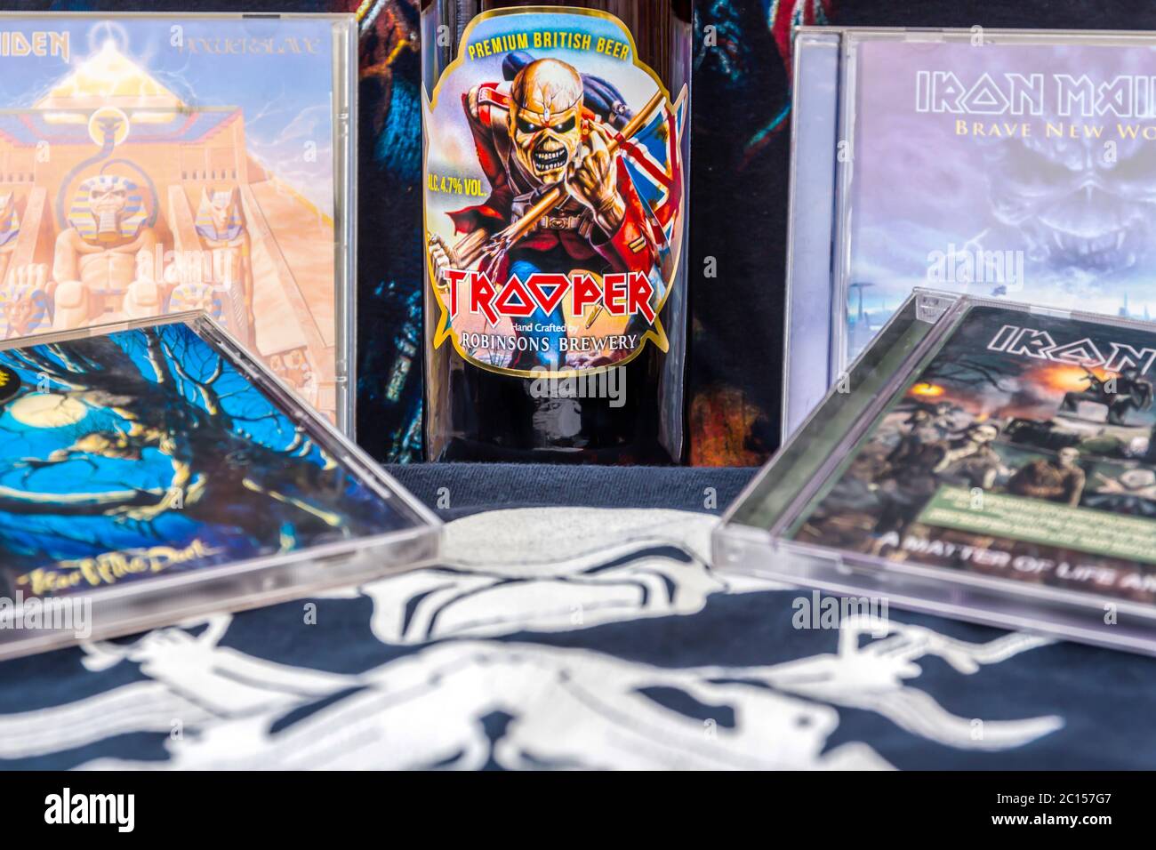 Una vita still di cimeli della Heavy Metal Band, Iron Maiden, con CD, T-shirt e una bottiglia di birra con il logo Trooper sulla parte anteriore Foto Stock