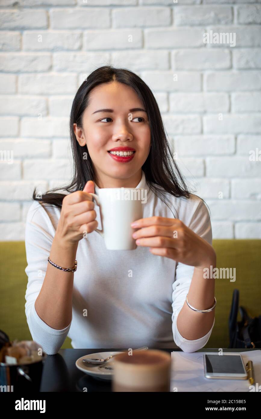 Donna asiatica che ha una tazza di caffè in un ritratto closeup bar Foto Stock