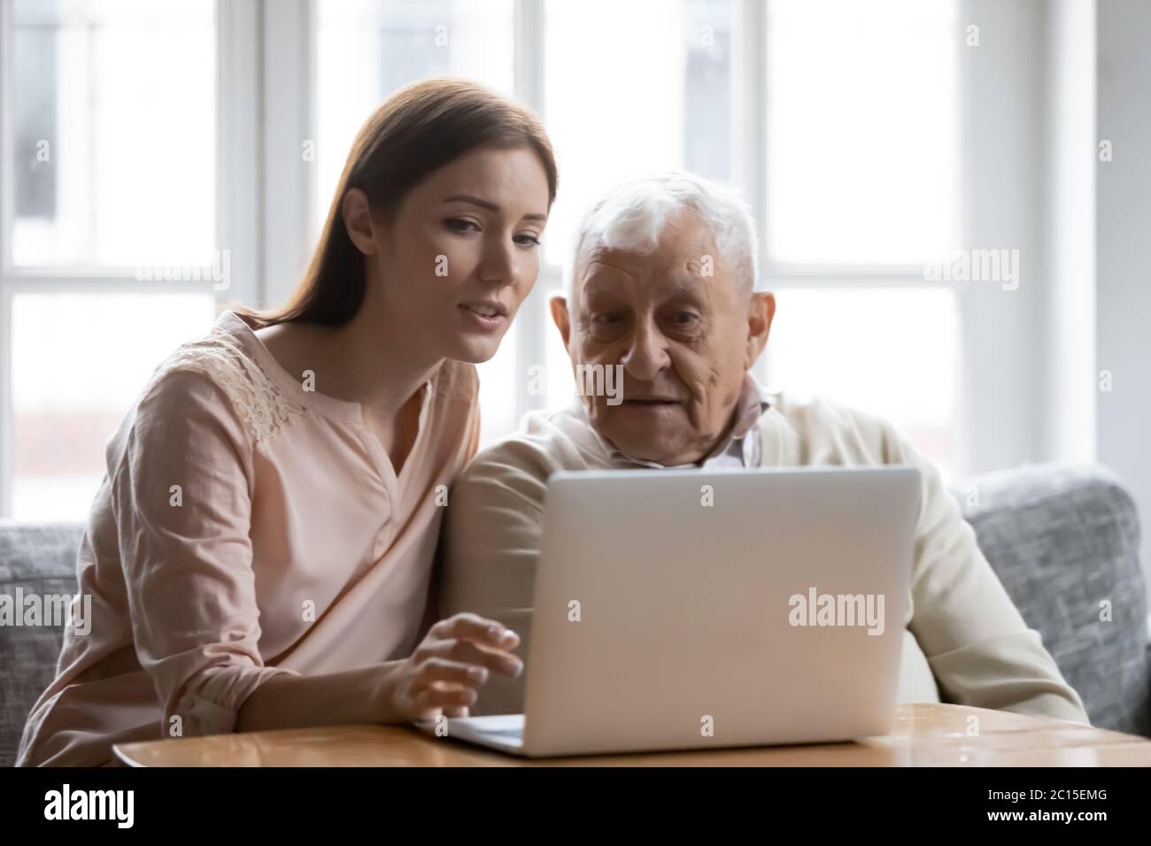 Figlia di ringhiup che si prende cura insegnando ad anziano padre ad usare il laptop Foto Stock