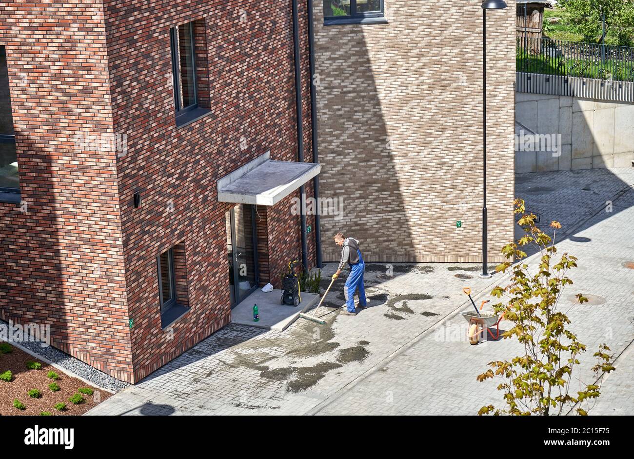 Lavoratore che riempie le tegole con sabbia vicino ai nuovi edifici Foto Stock