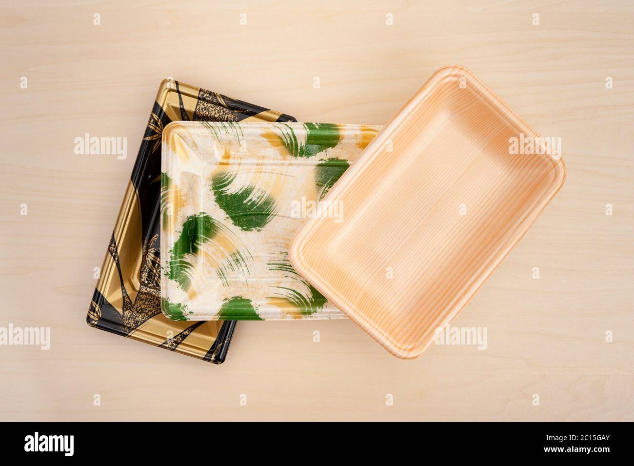 Vassoi colorati per contenitori di alimenti in schiuma (vassoi in polistirolo) impilati. Isolato su sfondo di legno. Primo piano. Shot orizzontale. Foto Stock