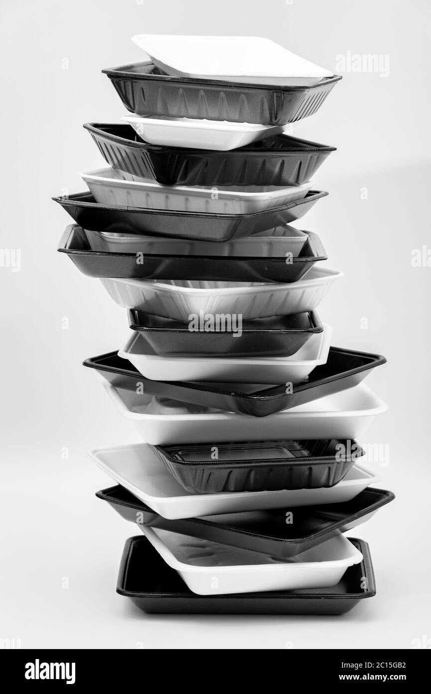 Vassoi per contenitori di alimenti in schiuma bianca e nera (vassoi in polistirolo) impilati. Isolato su sfondo bianco. Primo piano. Shot verticale. Foto Stock
