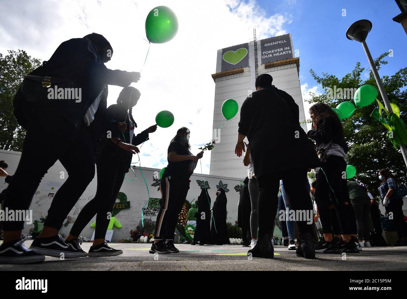 La gente rilascia palloncini presso il Mosaico della comunità commemorativa di Grenfell alla base del blocco della torre di Londra il terzo anniversario dell'incendio della Torre di Grenfell, che ha causato 72 vittime il 14 2017 giugno. Foto Stock
