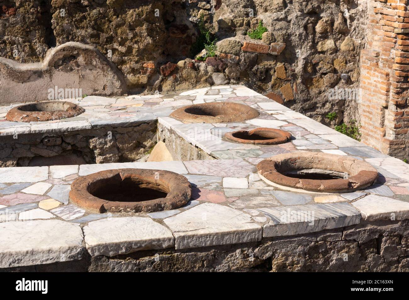 Roman Grande Taberna (fast food) con bancone rivestito in marmo e contenitori in ceramica argilleria nell'antica città di Ercolano, Italia Foto Stock