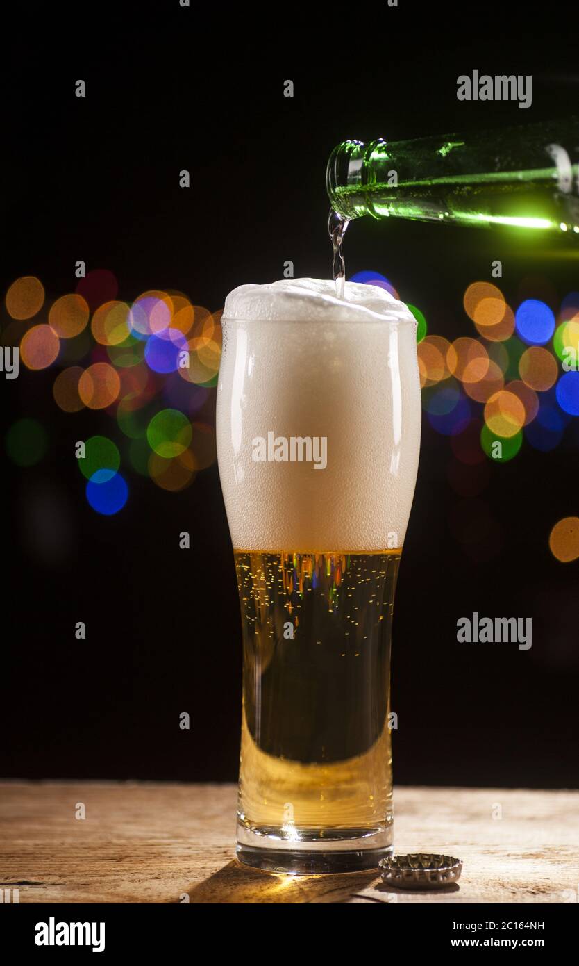La birra si versa in un bicchiere sullo sfondo delle luci del bar Foto Stock La birra si versa in un bicchiere sullo sfondo delle luci del bar Foto Stock