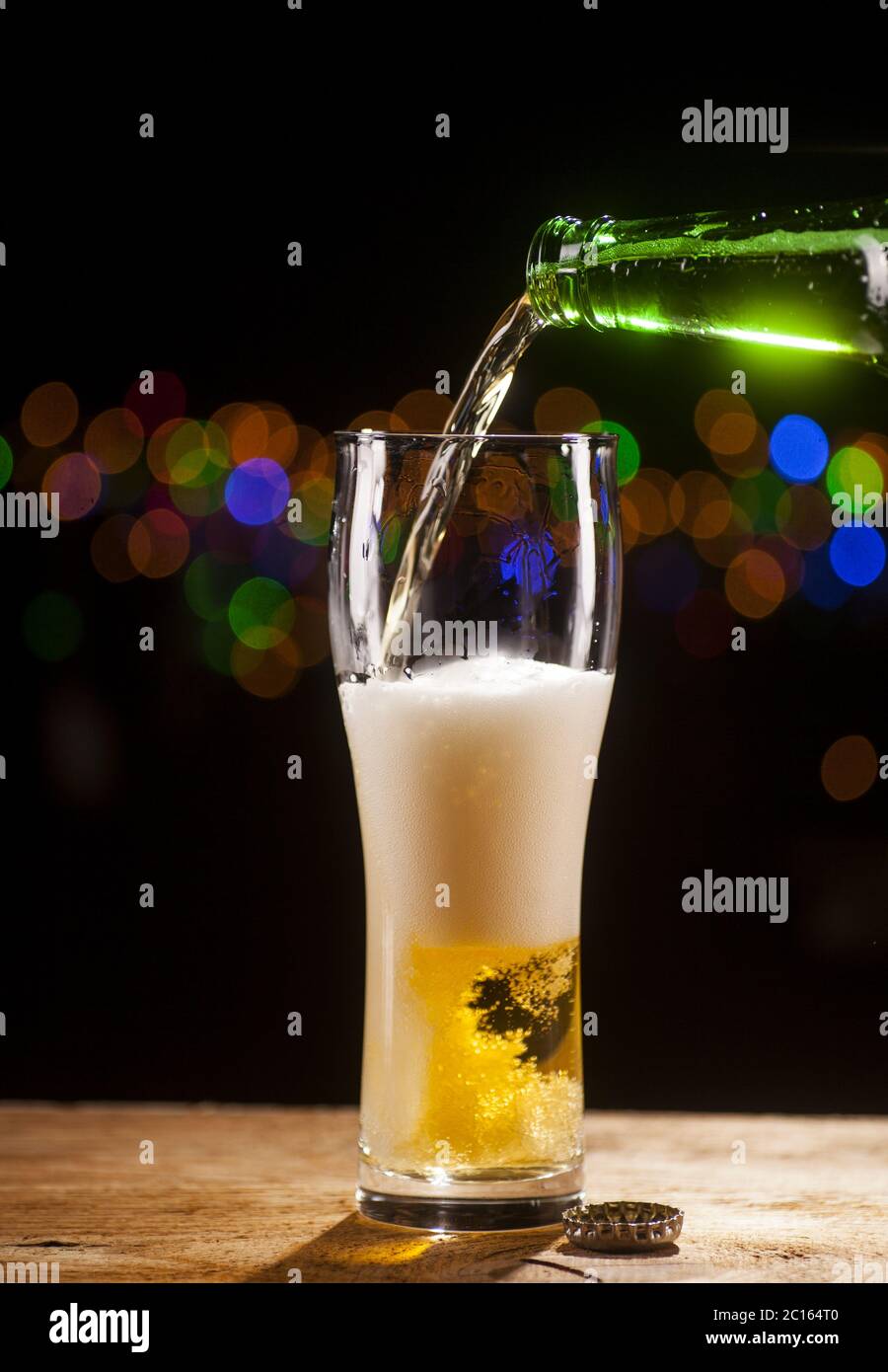 La birra si versa in un bicchiere sullo sfondo delle luci del bar Foto Stock La birra si versa in un bicchiere sullo sfondo delle luci del bar Foto Stock