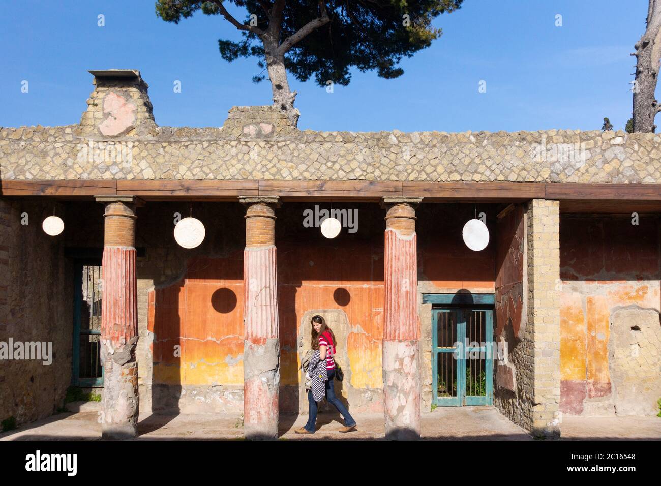 Casa del rilievo del Telefus con copie di dischi di marmo chiamati oscilla sospesi tra le colonne dipinte nell'antica città romana di Ercolano Foto Stock