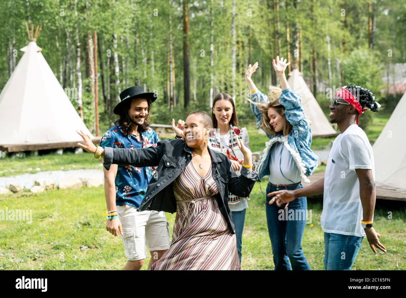 Giovani energici multietnici che ballano al festival musicale situato nella foresta Foto Stock