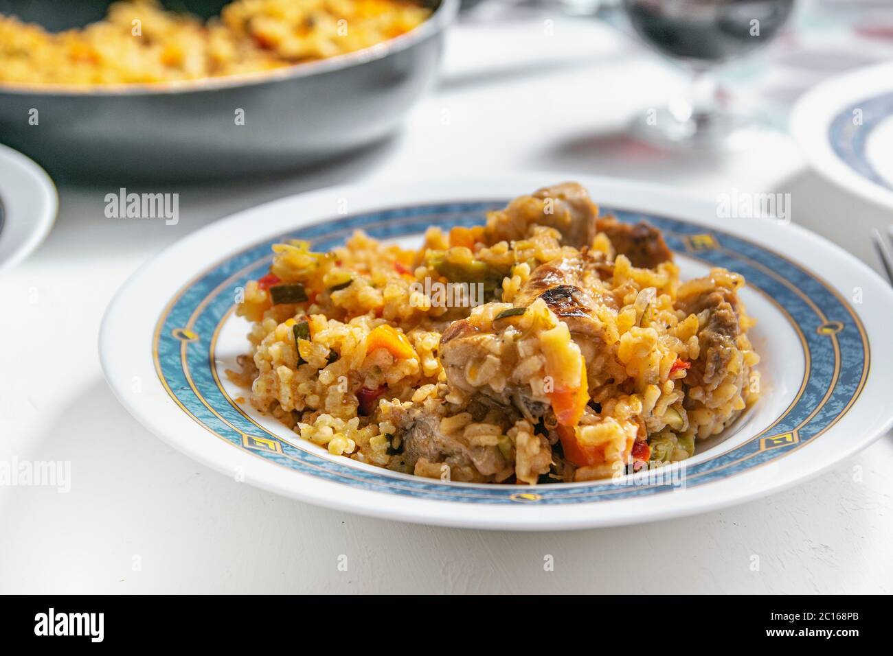 Riso tipico spagnolo con ricetta di coniglio e verdure servito su un piatto bianco. Spazio di copia vuoto per il contenuto dell'editor. Foto Stock