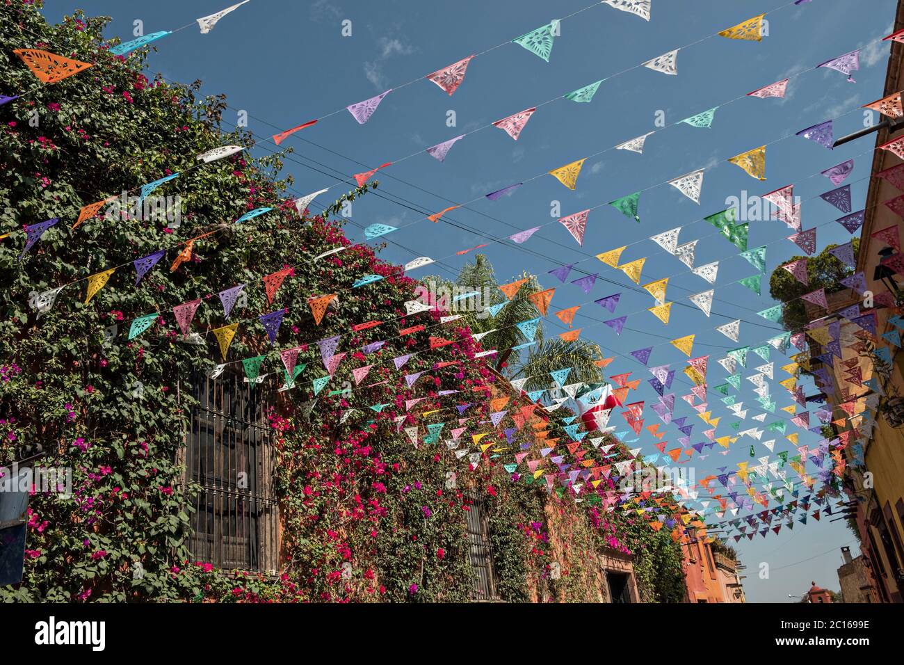 Banner fiesta di carta chiamato papel picado contro un cielo blu e classico edificio coloniale lungo Calle Quebrada nel quartiere storico di San Miguel de Allende, Messico. Foto Stock