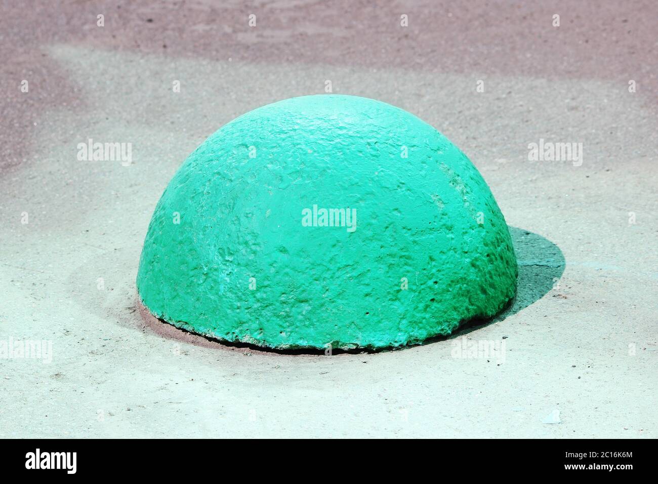 I supporti in cemento a forma di sfera accanto alla strada contro l'ingresso dei veicoli, che è evidenziato dal riflesso del gre Foto Stock