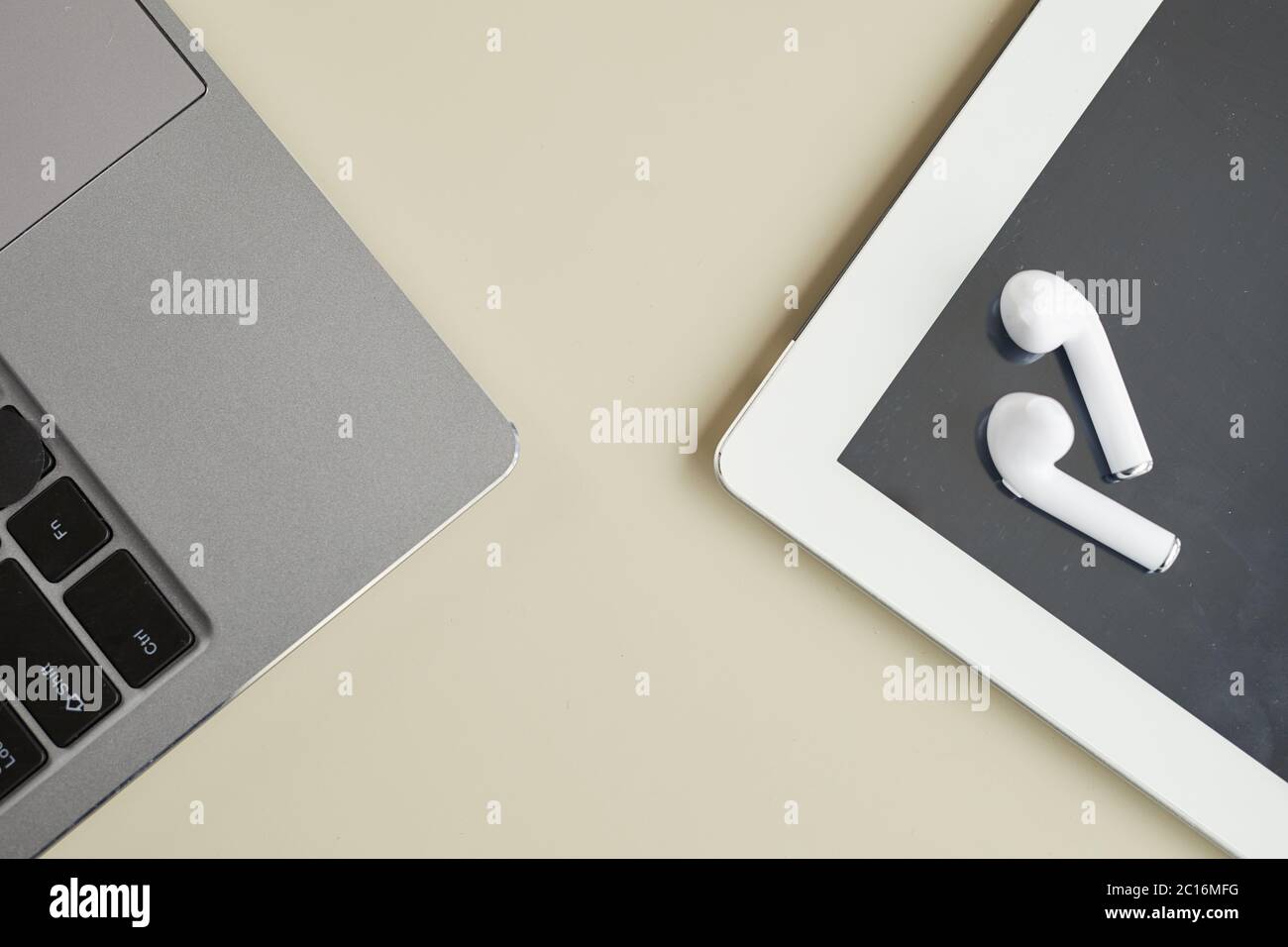 Vista dall'alto primi piano dei dispositivi tecnologici moderni laptop, tablet e auricolari wireless su uno sfondo minimo, spazio di copia Foto Stock