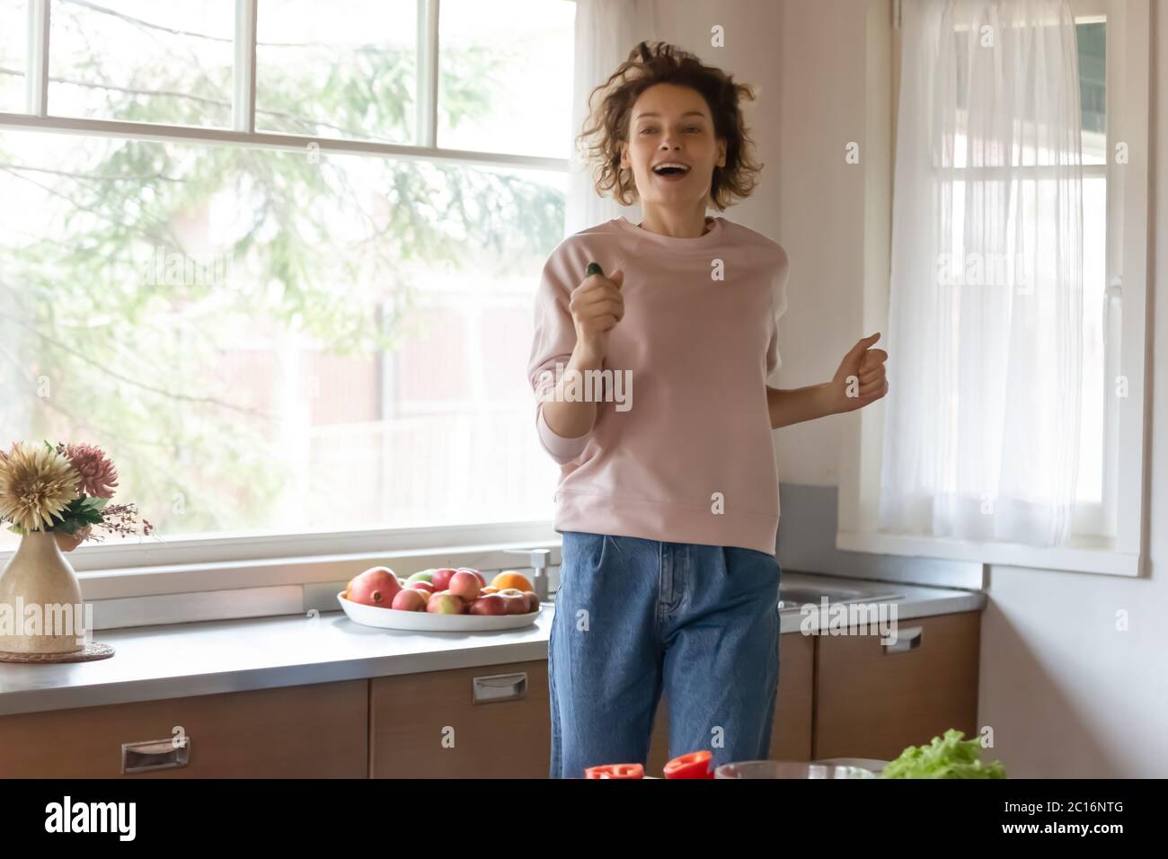 Felice giovane donna avere divertimento cucinare a casa Foto Stock