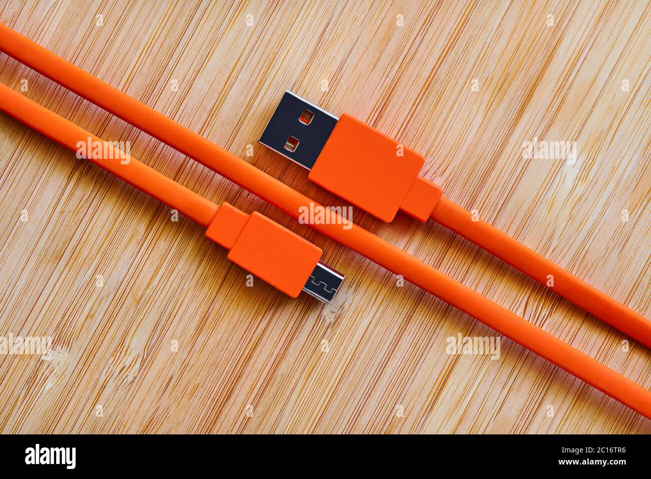 Cavo USB arancione per gadget su sfondo in legno Foto Stock