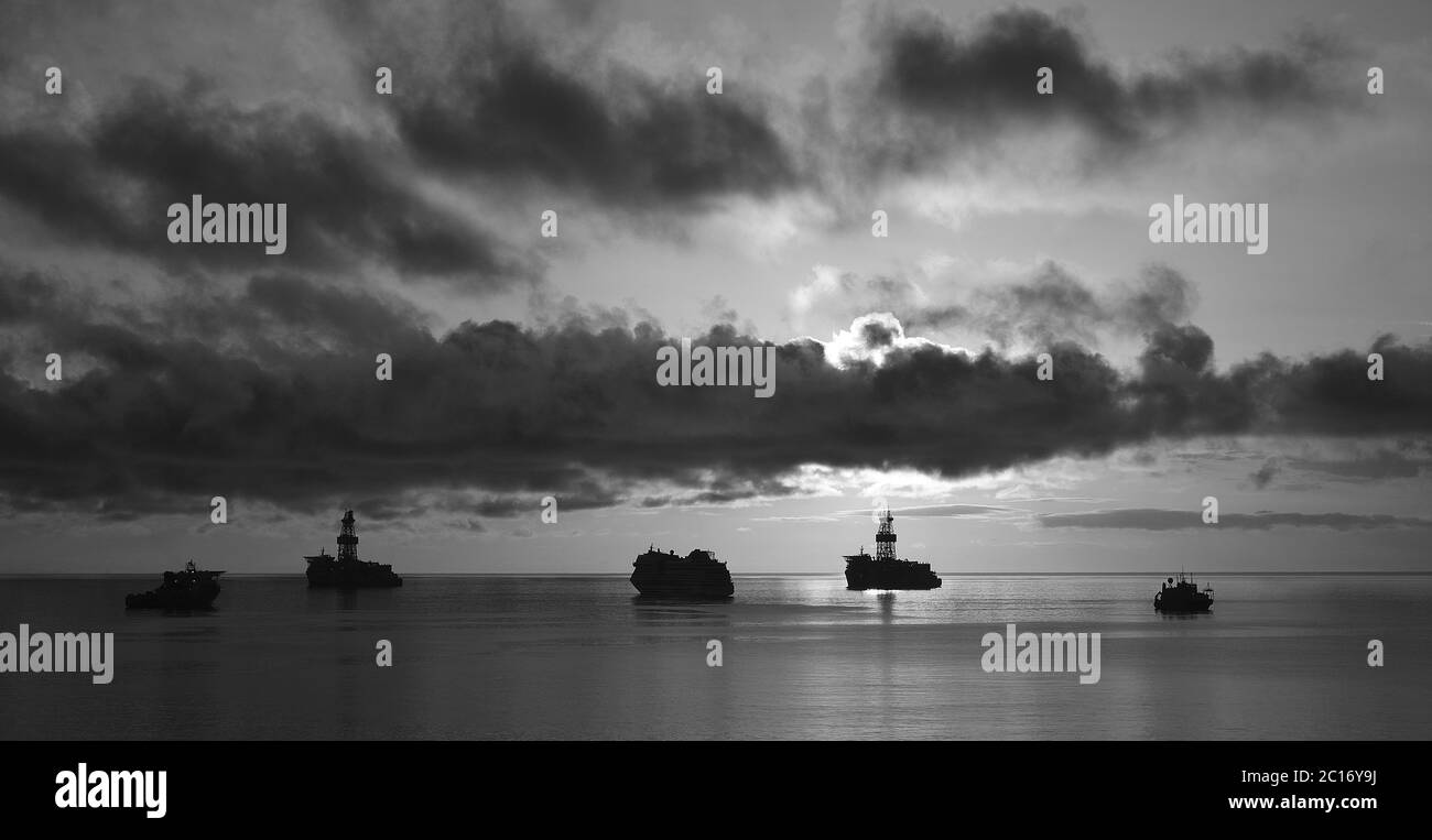 Panoramica dalla baia all'alba con cielo nuvoloso, navi e mare calmo, bianco e nero Foto Stock