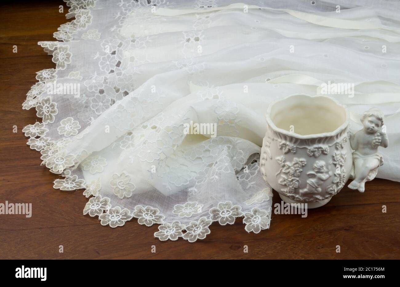 Abito in pizzo bianco da polso su tavolo in legno con coppa in ceramica Foto Stock