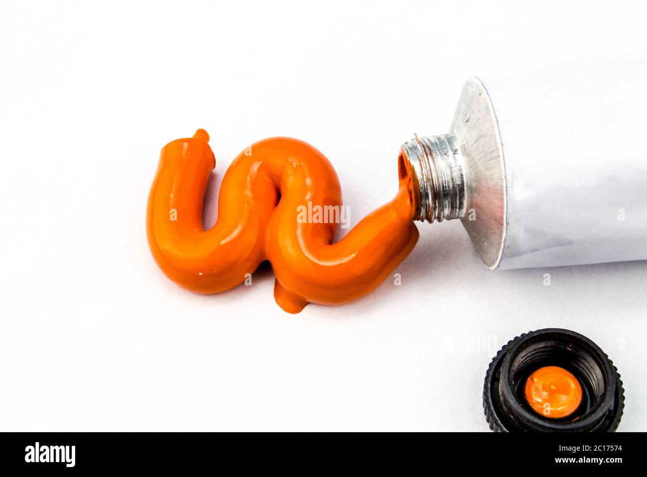 Arancione vernice arte spremuto fuori del tubo su sfondo bianco Foto Stock