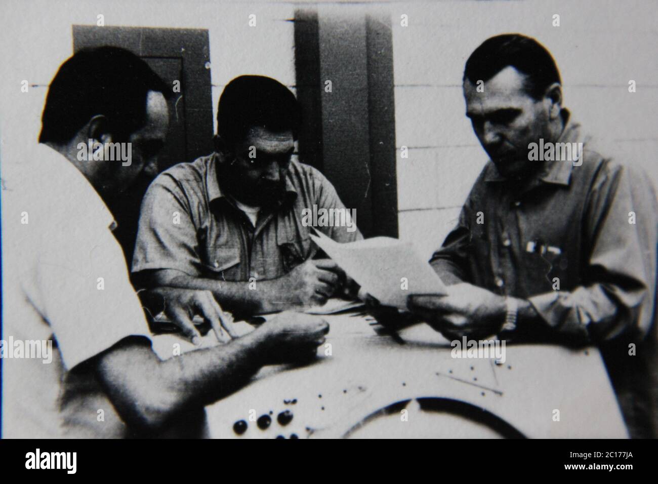 Fine anni '70 vintage in bianco e nero fotografia estrema di tre ragazzi regolari che lavorano sul lavoro in una sessione di gruppo. Foto Stock