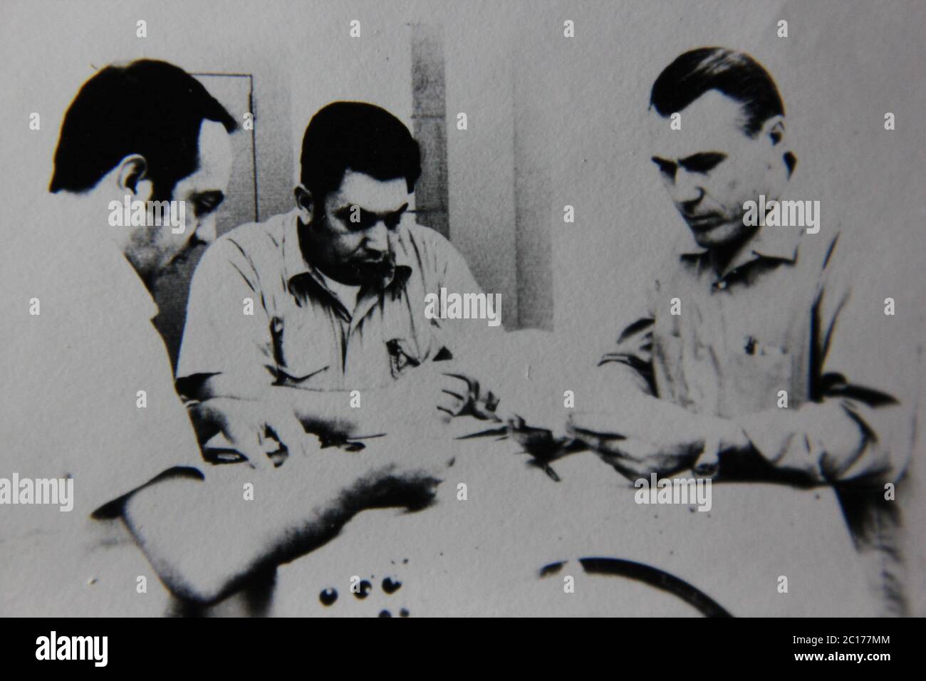 Fine anni '70 vintage in bianco e nero fotografia estrema di tre ragazzi regolari che lavorano sul lavoro in una sessione di gruppo. Foto Stock