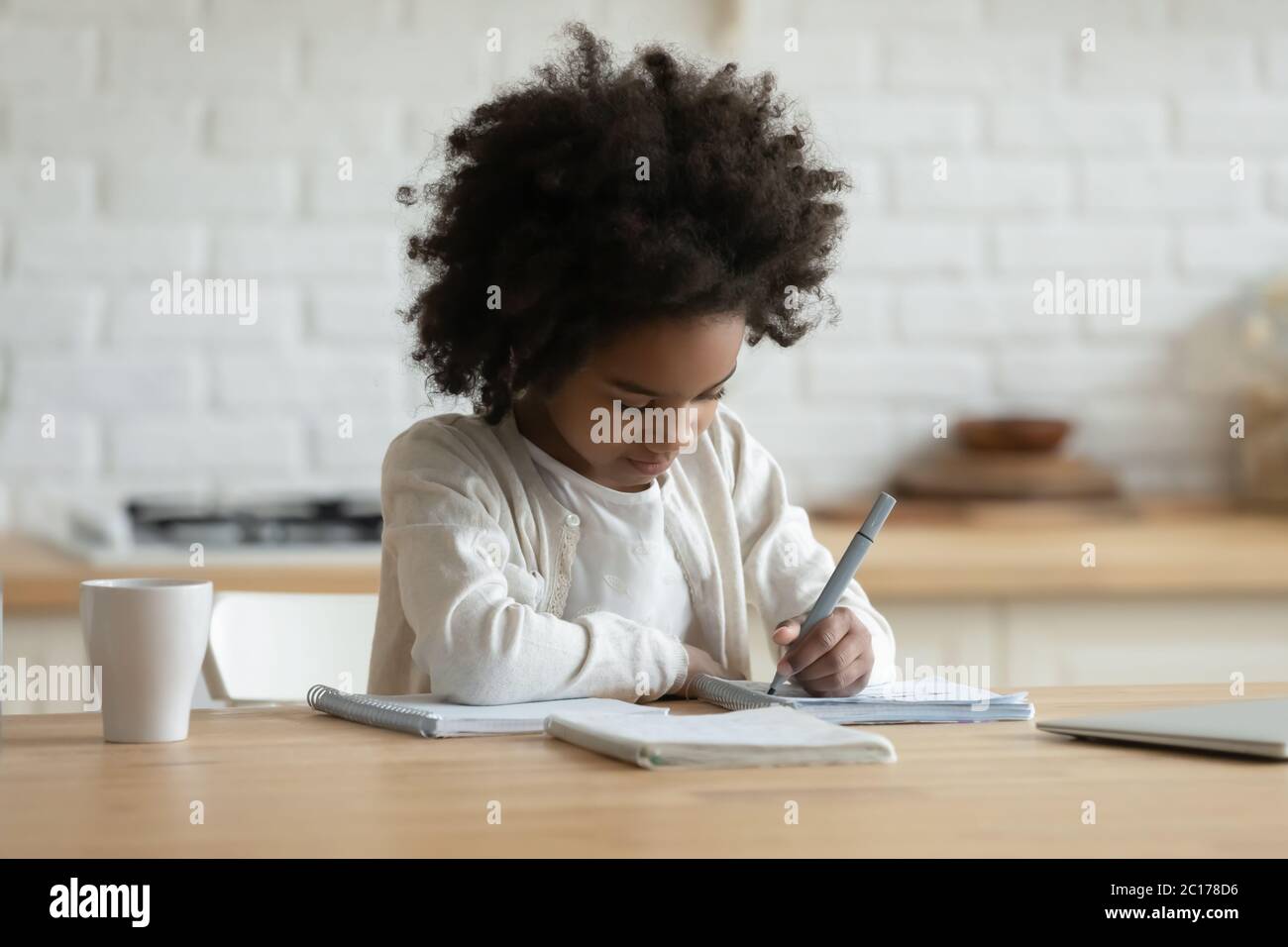 Ragazza africana seduta facendo compiti imparare soggetto scolastico a casa Foto Stock