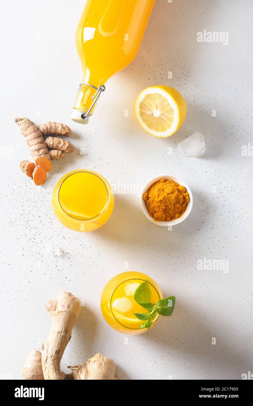 Jamu bevanda indiana di curcuma, zenzero, limone su sfondo bianco. Verticale. Vista dall'alto. Foto Stock