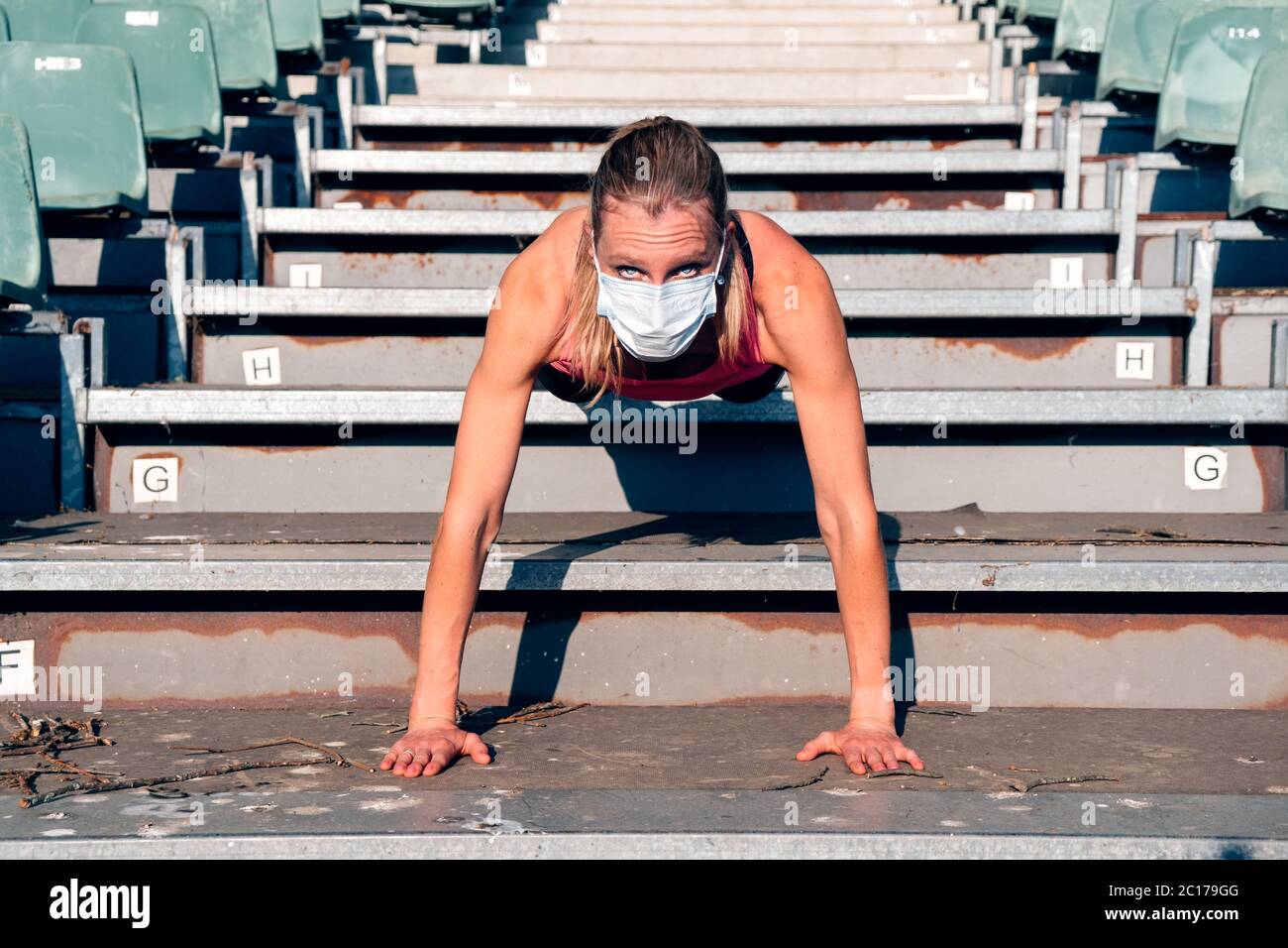 donna sana che fa sport ai gradini dello stadio - donna che fa l'allenamento indossando una maschera protettiva Foto Stock