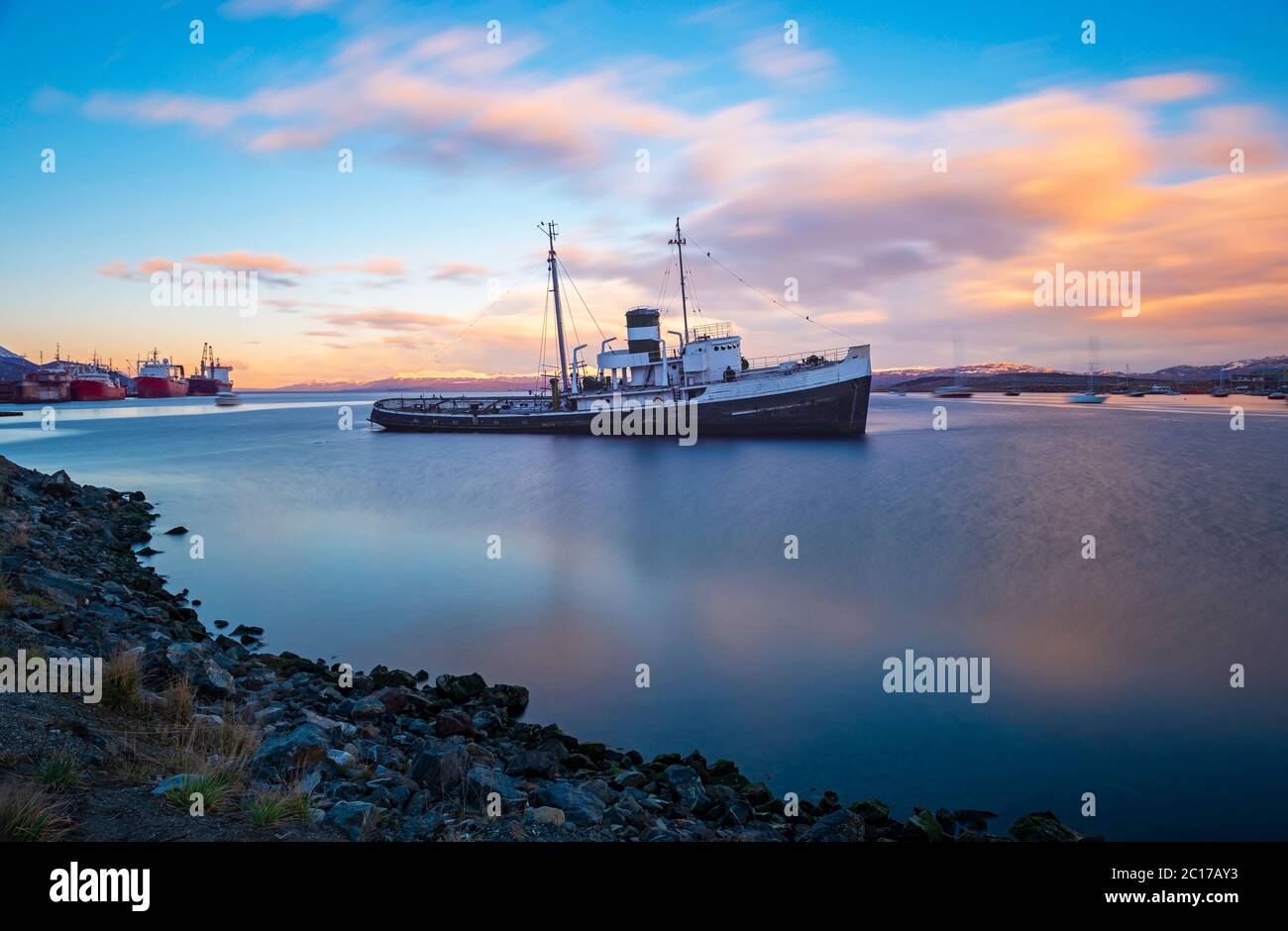 Lunga esposizione di una barca all'ancora nel porto di Ushuaia al tramonto, canale di Beagle, Argentina. Foto Stock