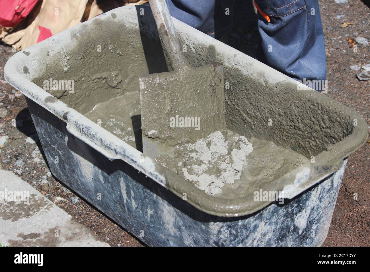 L'operaio inginocchiato cemento per fissare la fondazione del supporto sotto i semafori vicino alla strada con l'aiuto di un bagno e. Foto Stock