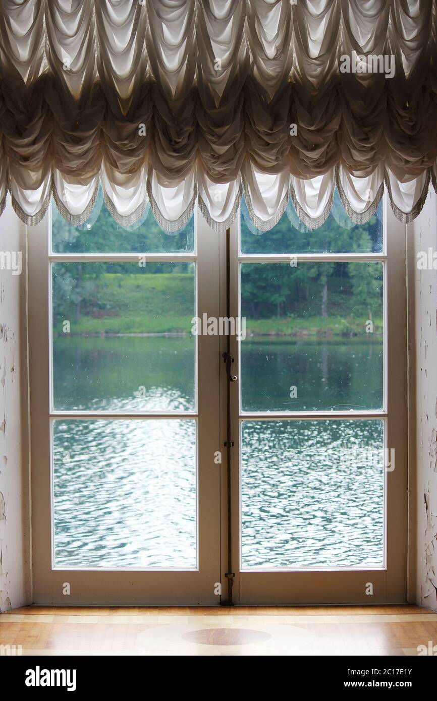 Luce dalla finestra con il bianco tende francese e una vista del lago. Foto Stock