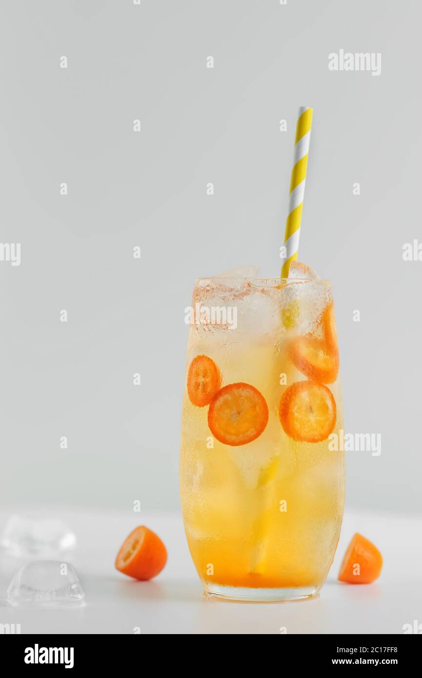 Bevanda estiva agli agrumi con arance, kumquat e cubetti di ghiaccio su sfondo bianco. Foto Stock