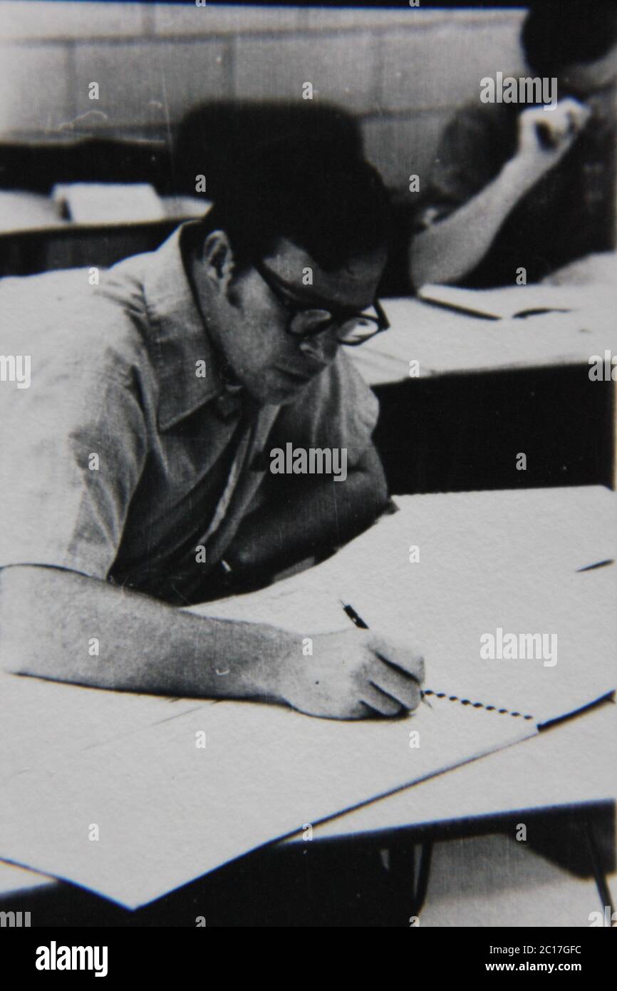 Fine anni '70 vintage in bianco e nero fotografia estrema di un uomo professionista che lavora su disegni enormi e documenti. Foto Stock