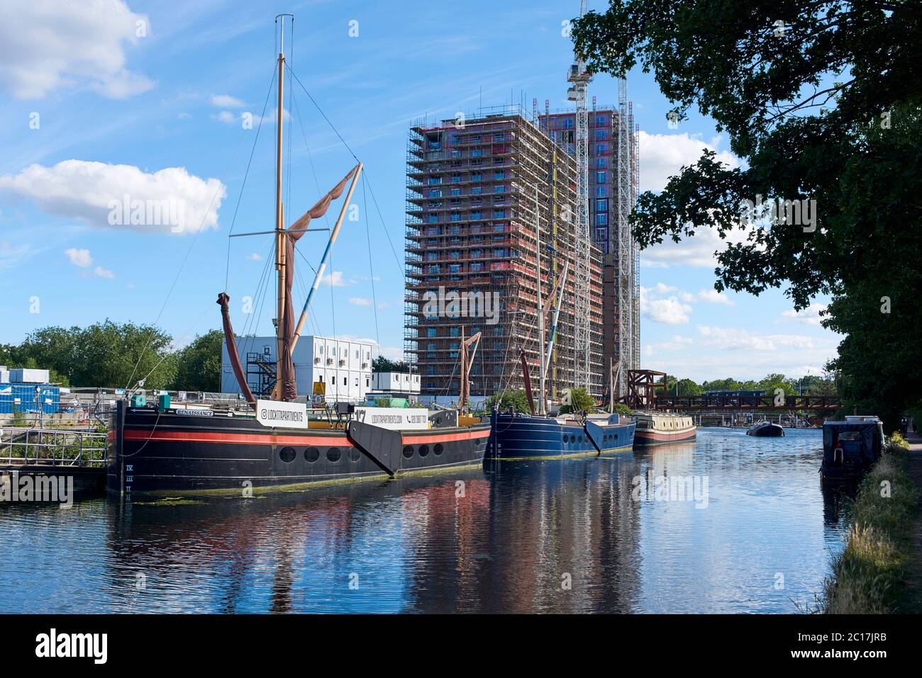 Il fiume Lea a Tottenham Hale, Londra del nord Regno Unito, con chiatte fluviali e il nuovo Hale Wharf di sviluppo di alloggi in costruzione Foto Stock