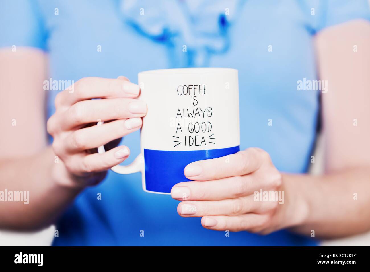Le mani femminili tengono una tazza di caffè blu bianco Foto Stock