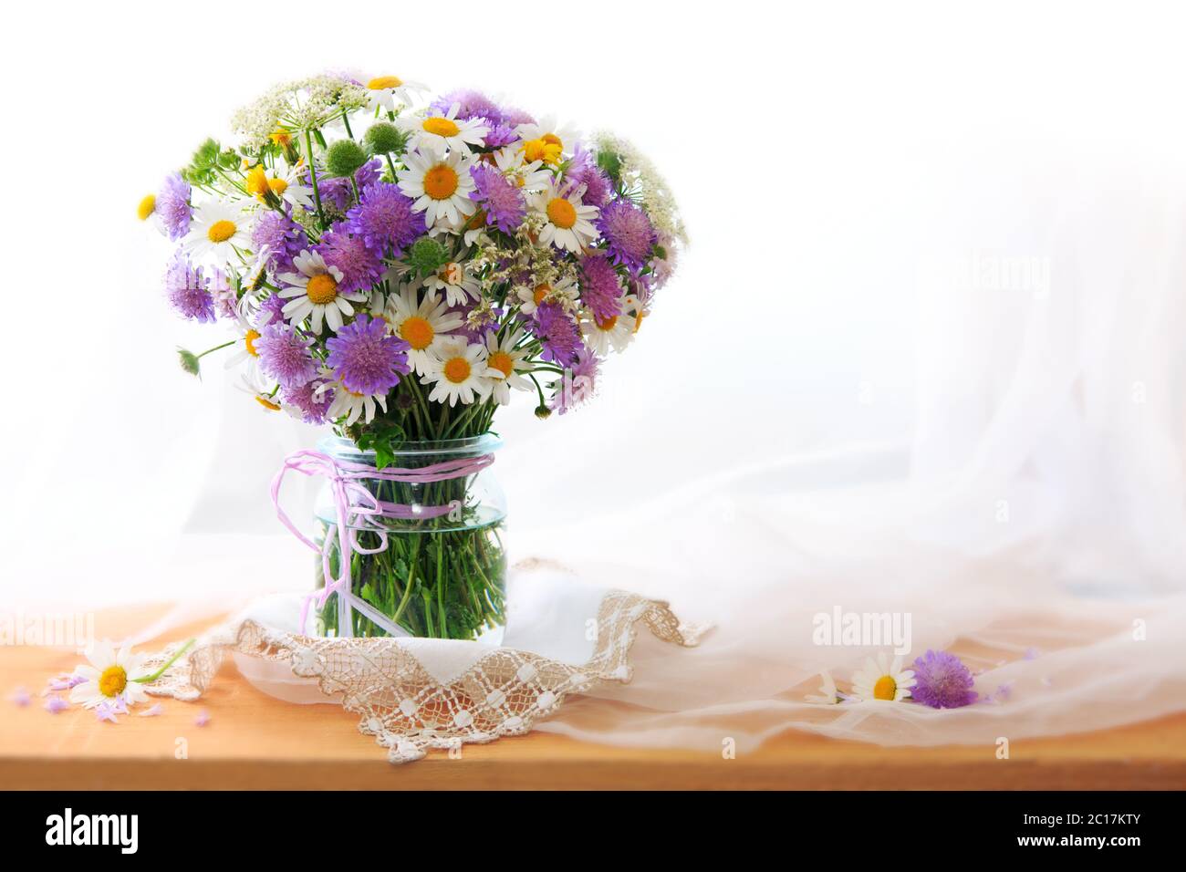 Chamomiles bouquett in vaso su fondo tessuto. Foto Stock