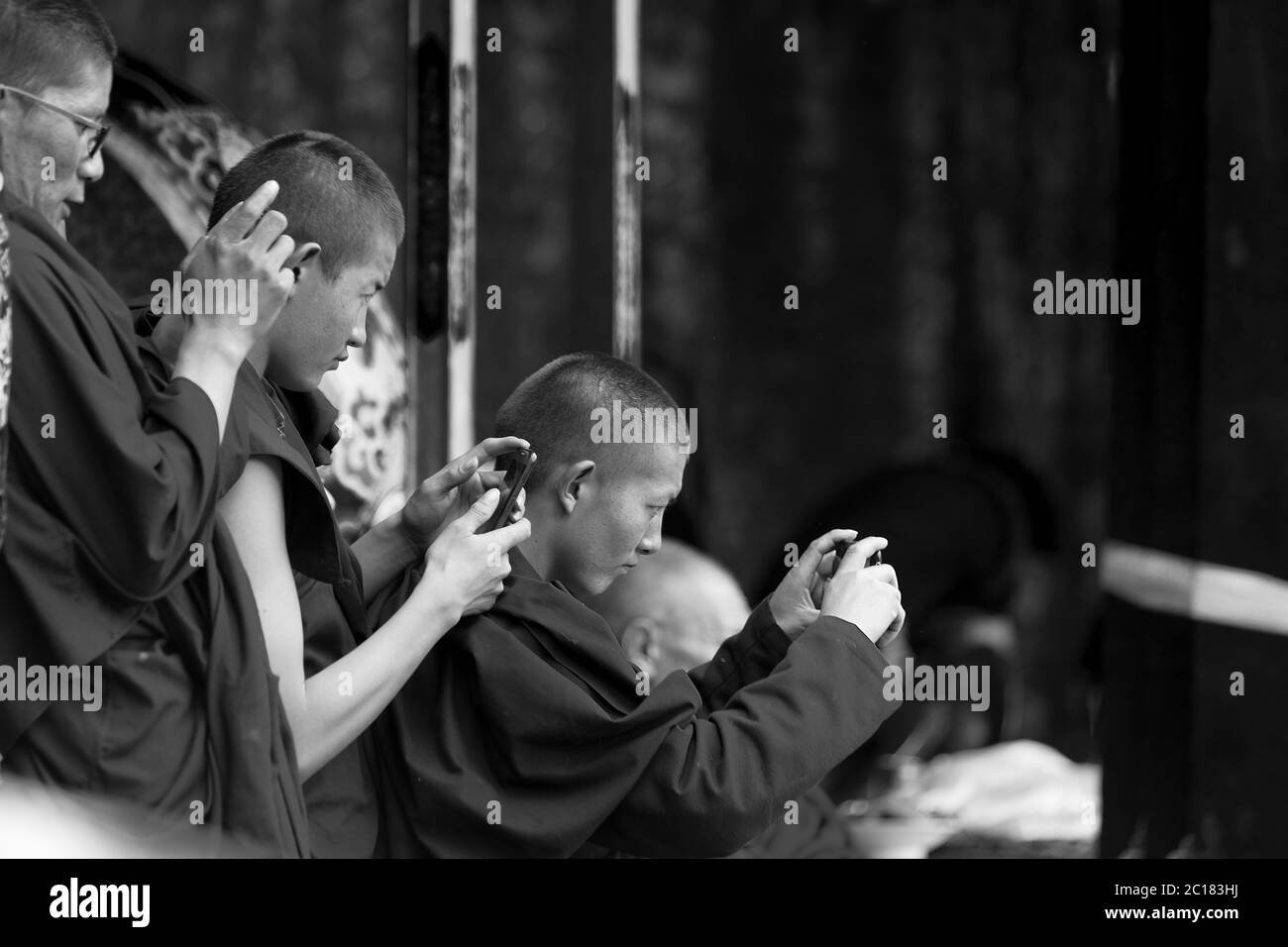 I giovani monaci scattano foto della danza sacra cham sui loro telefoni cellulari, Tsurphu, Tibet Foto Stock