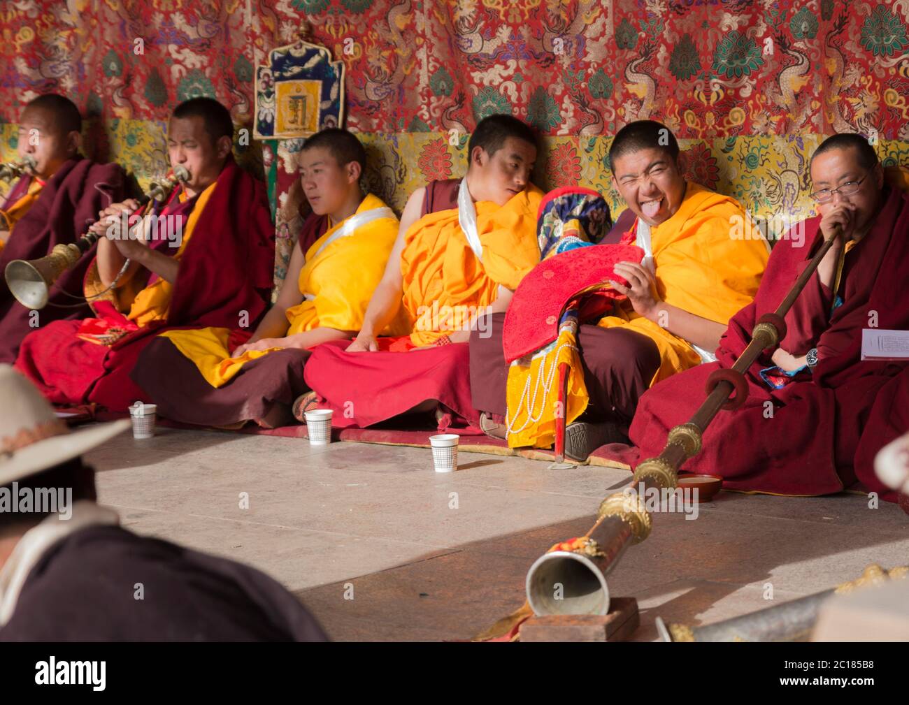 Un novizio malizioso tira un volto nel mezzo della cerimonia, Tsurphu festival monastero, Tibet Foto Stock