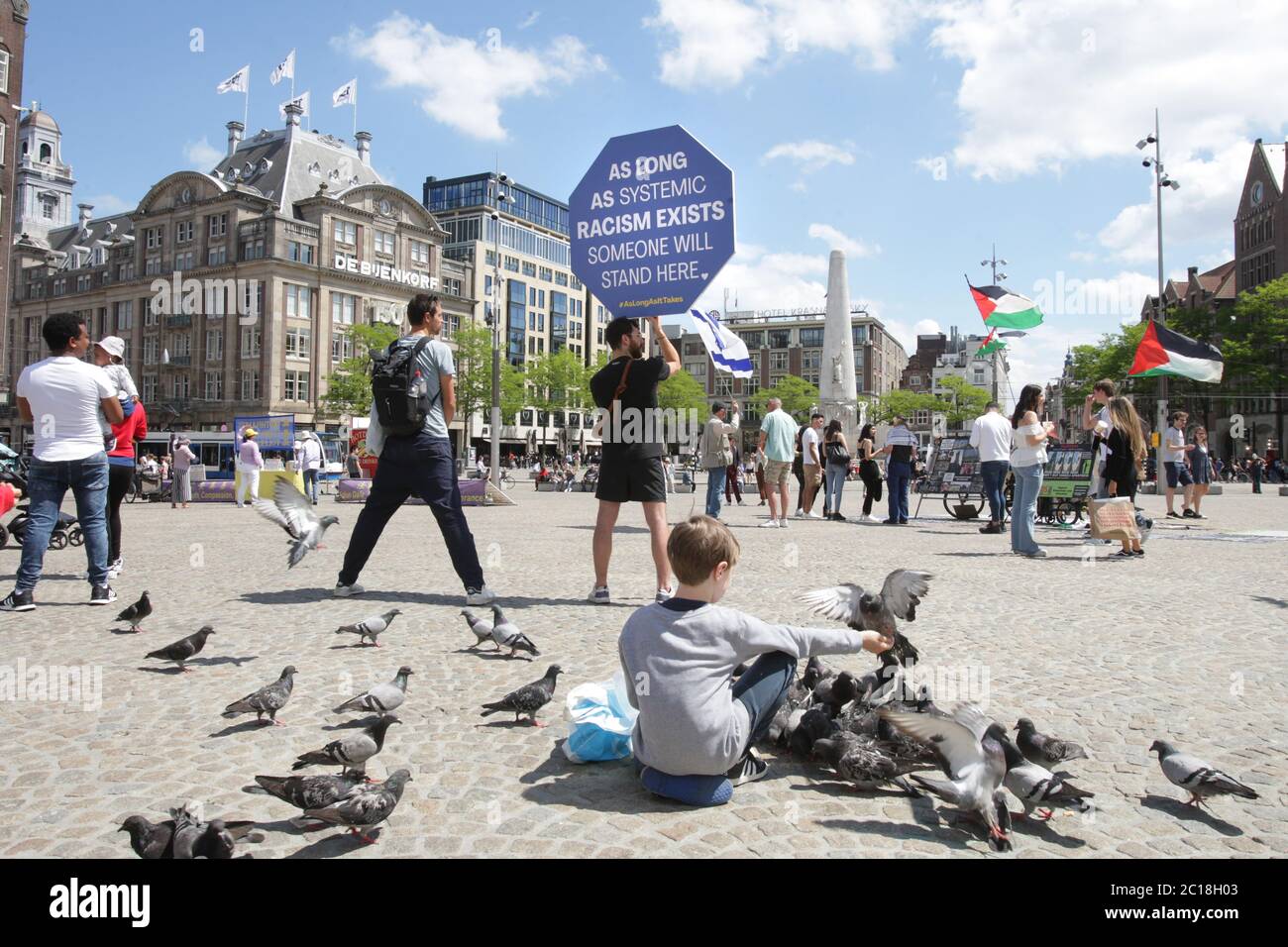 Un ragazzo mangerà i piccioni e un protestore tiene un cartello con il segno ‘finché esiste un razzismo sistemico, qualcuno si leverà qui’ durante l’antirazzismo Foto Stock