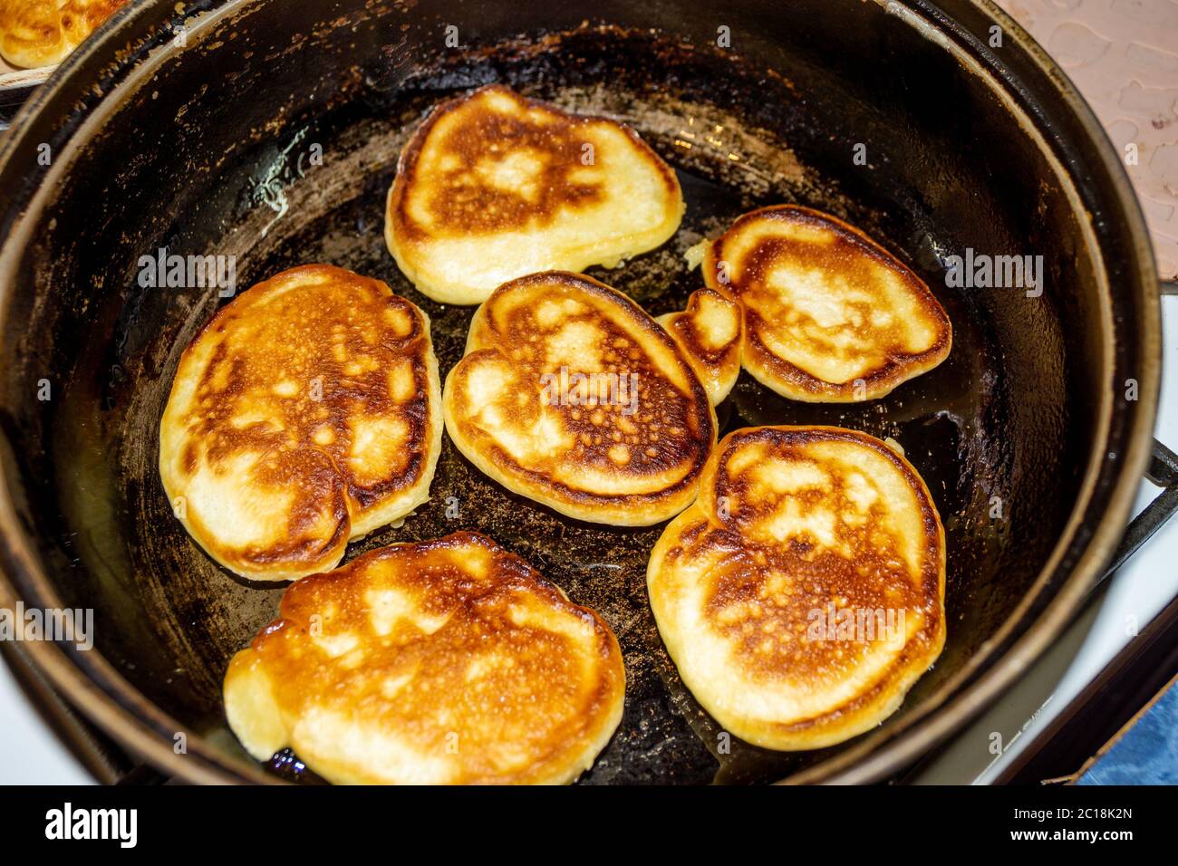 deliziose frittelle vengono fritte in una padella nera che trasuda l'aroma  di dolci freschi, che ricorda la vecchia casa e la nonna Foto stock - Alamy