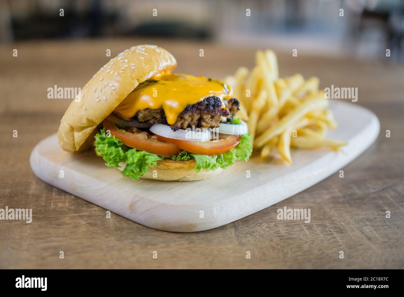 Hamburger fatto in casa con manzo, cipolla, pomodoro, lattuga e formaggio. Hamburger fresco con patatine fritte e condimenti. Foto Stock