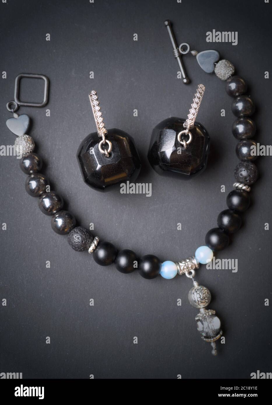 Gioiello artigianale di bracciale con pietre semipreciouse e orecchini con nero semipreziose gem getto su sfondo nero Foto Stock