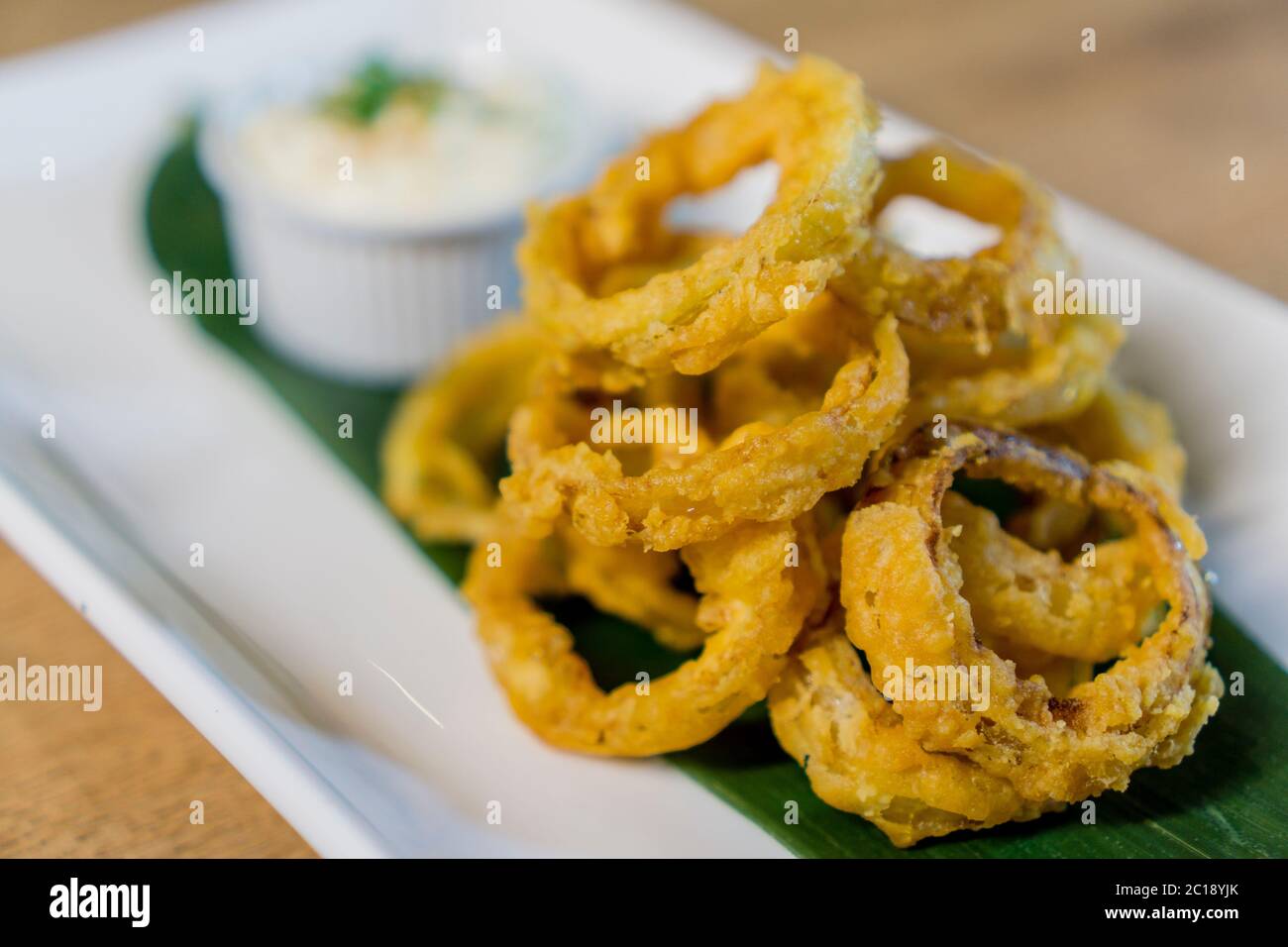 Anello di cipolla fritto e profondo servito con panna acida. Foto Stock