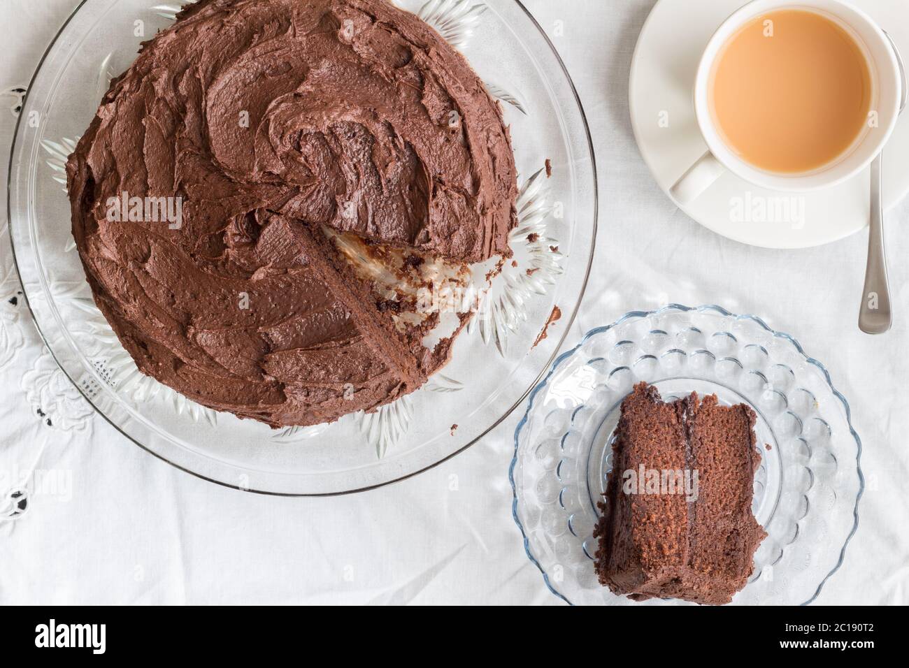 Torta al cioccolato e fetta di piatto da portata e tazza di tè su panno da tavolo bianco - immagine dall'alto Foto Stock