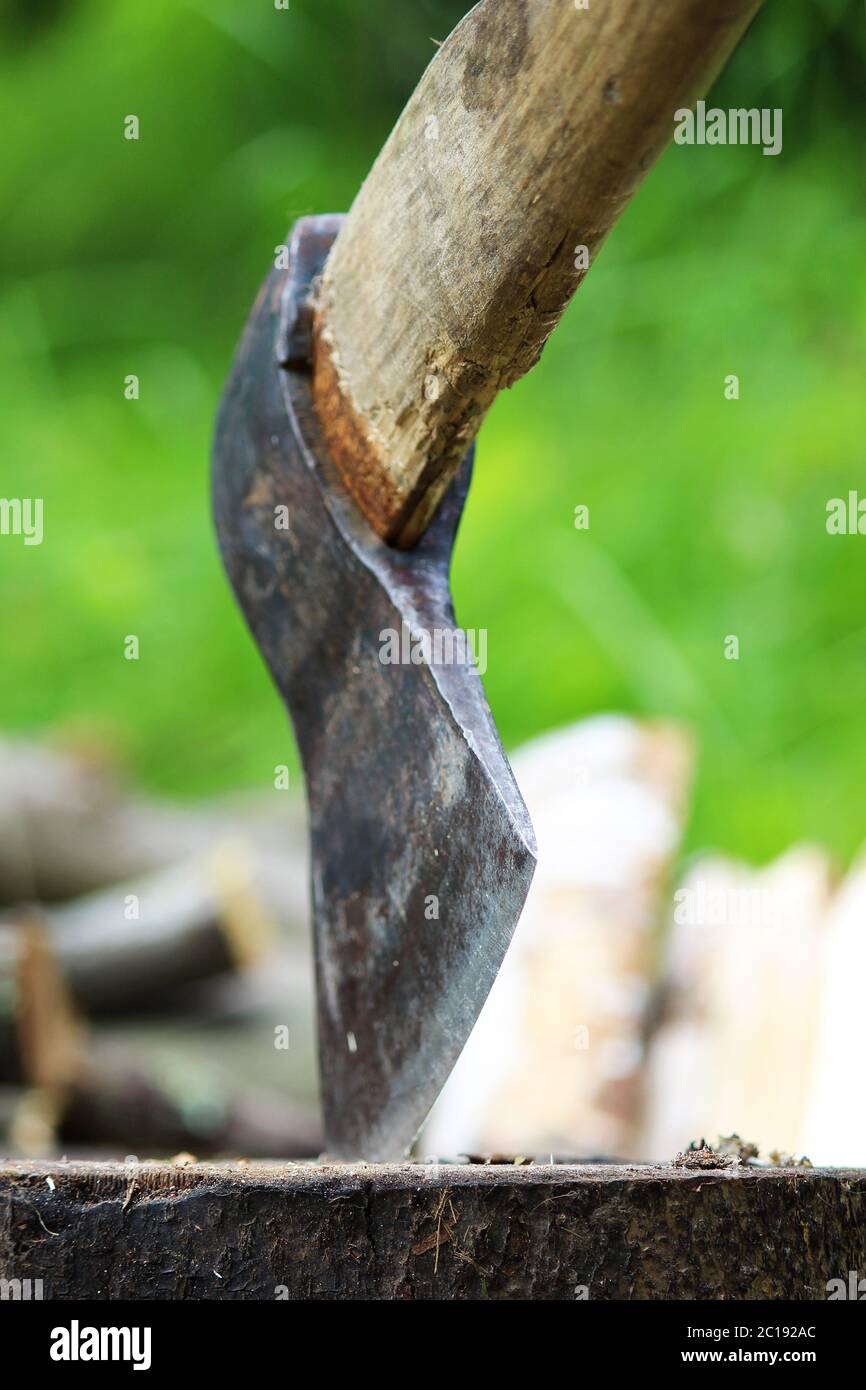 Una lama affilata di un'ascia che si stacca in un legno di cuneo. Concetto rustico. Foto Stock